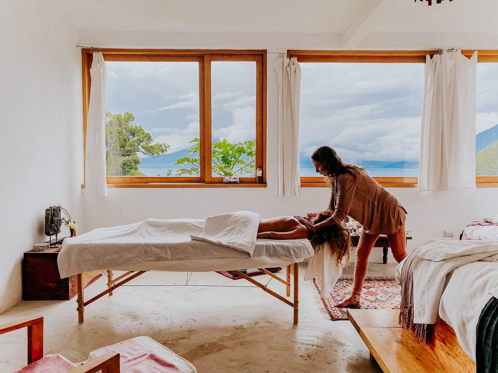 Therapeutic massage in a sunlit lake-view treatment room at The Seed
